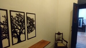 A hallway with a wooden bench, three black wall art pieces, and a chair. - Pousada e Hostel Andarai (Andaraí)