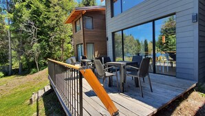 A modern two-story building with a deck featuring outdoor furniture and large windows. - Hygge Haus (Villa La Angostura)