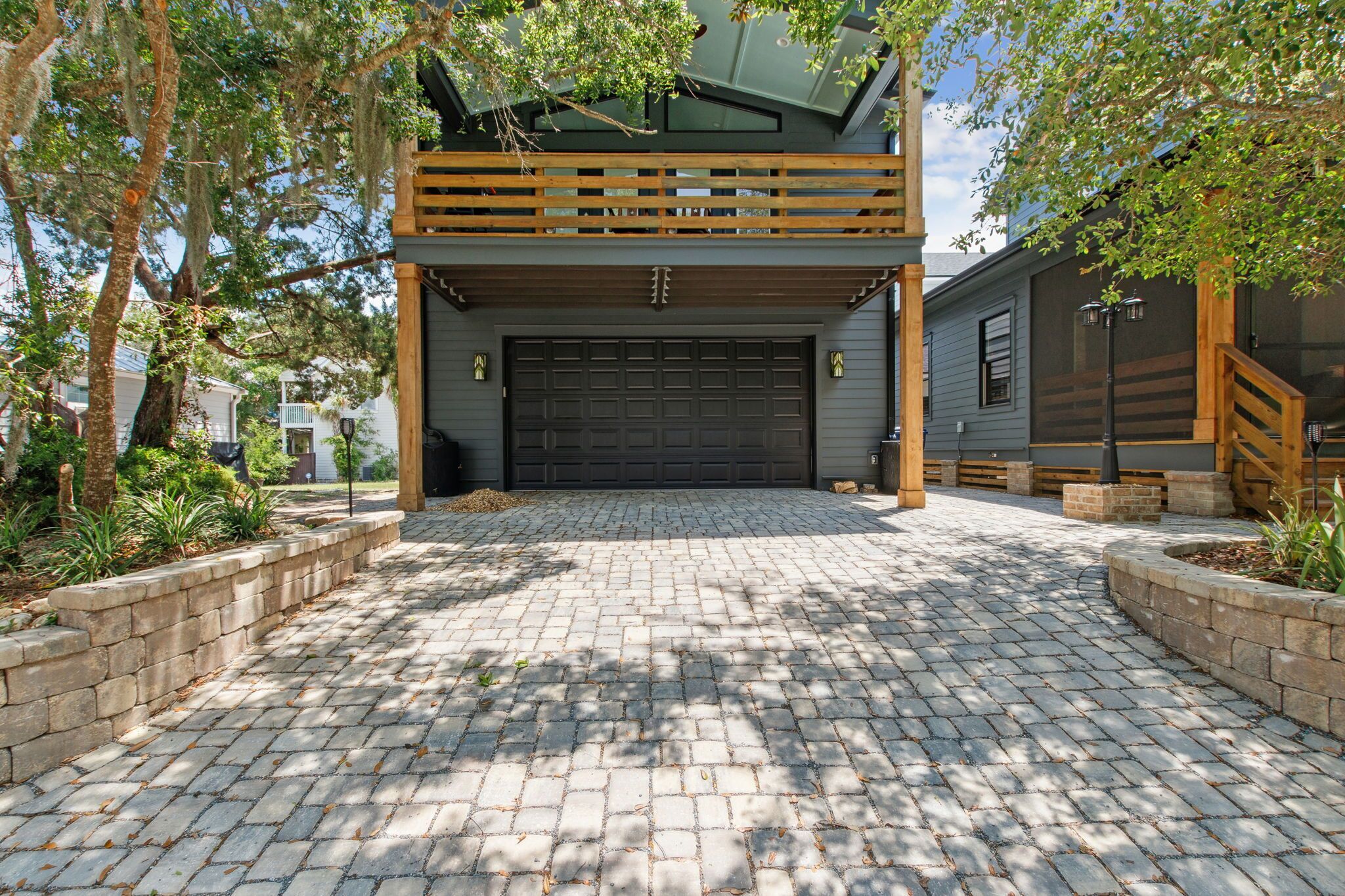 A two-story house with a garage, paved driveway, and wooden deck.