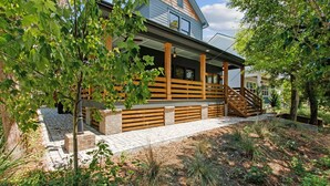 Ein modernes Haus mit einer Holzterrasse, einem Backsteinfundament und einer Treppe, die zum Eingang führt.