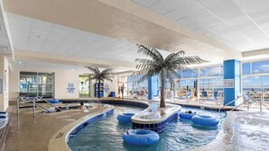 An indoor swimming pool with palm trees, lounge chairs, and a sign prohibiting diving. - Unforgettable Getaway 3BR (Myrtle Beach)