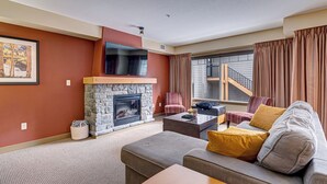 A living room with a stone fireplace, a sofa, a coffee table, and a television.