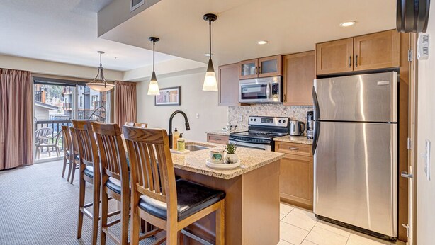 A modern kitchen with wooden cabinets, stainless steel appliances, and a central island with seating.