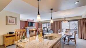A modern kitchen with granite countertops, a sink, and pendant lighting.