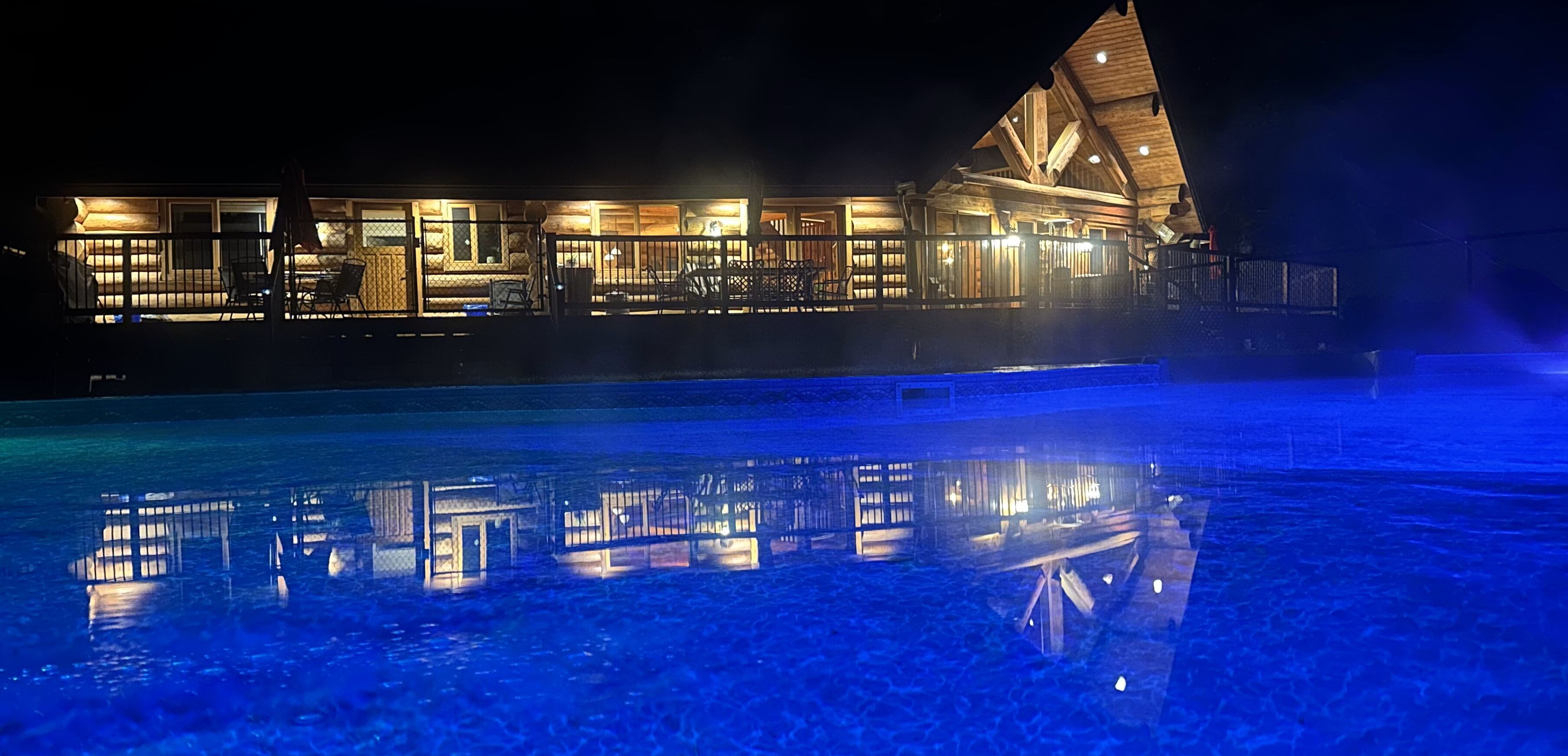 Un hotel frente al agua con piscina que refleja las luces del edificio.