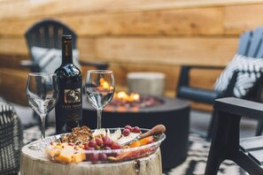 Un espace extérieur accueillant, avec une table en bois dressée pour un repas, deux verres à vin et une bouteille de vin Clos Pegase.