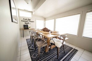 Un coin repas avec une table en bois, des chaises et un tapis à motifs noir et blanc.