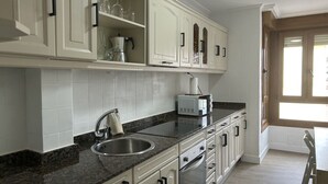 A kitchen with white cabinets, a granite countertop, a stainless steel sink, and a microwave.