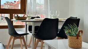 A modern dining area with a table, chairs, and a view of buildings outside.