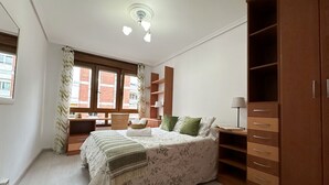 A bedroom with a bed, a wardrobe, a desk, and a chair.