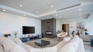Ein modernes Wohnzimmer mit großem Flachbildfernseher, Kamin und einer gemütlichen Sitzecke mit Sofa und Sessel.