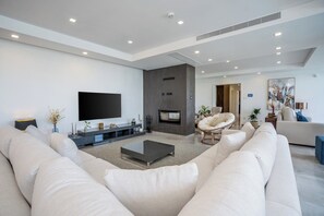 A modern living room with a large flat-screen TV, a fireplace, and a comfortable seating area with a sofa and a chair. - Luxury Private Villa | Casa da Colina (Caldas de Monchique)