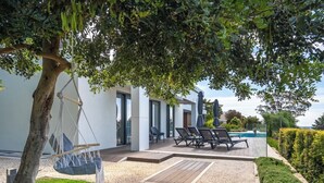 Eine moderne Außenpatio mit einer Hängematte, Liegestühlen und einem Swimmingpool.