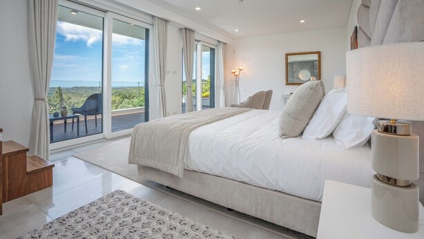 Ein Schlafzimmer mit einem großen Bett, Blick ins Freie und einem Balkon.