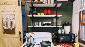 Une cuisine équipée d’une cuisinière, d’une bouilloire, d’un four à micro-ondes et d’une planche à découper avec des fraises.