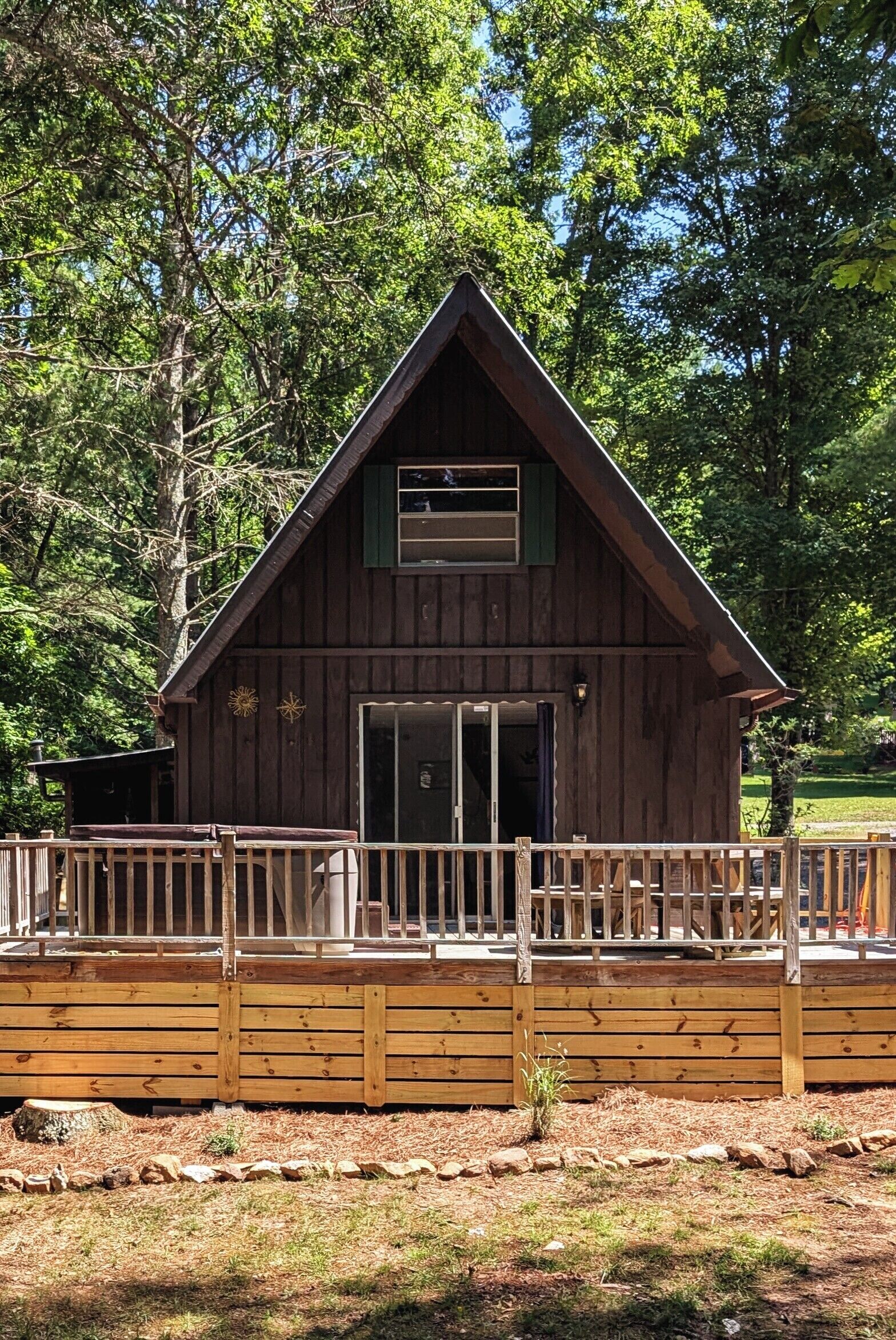 A wooden cabin with a sloped roof, a front door, and a small porch with a railing.