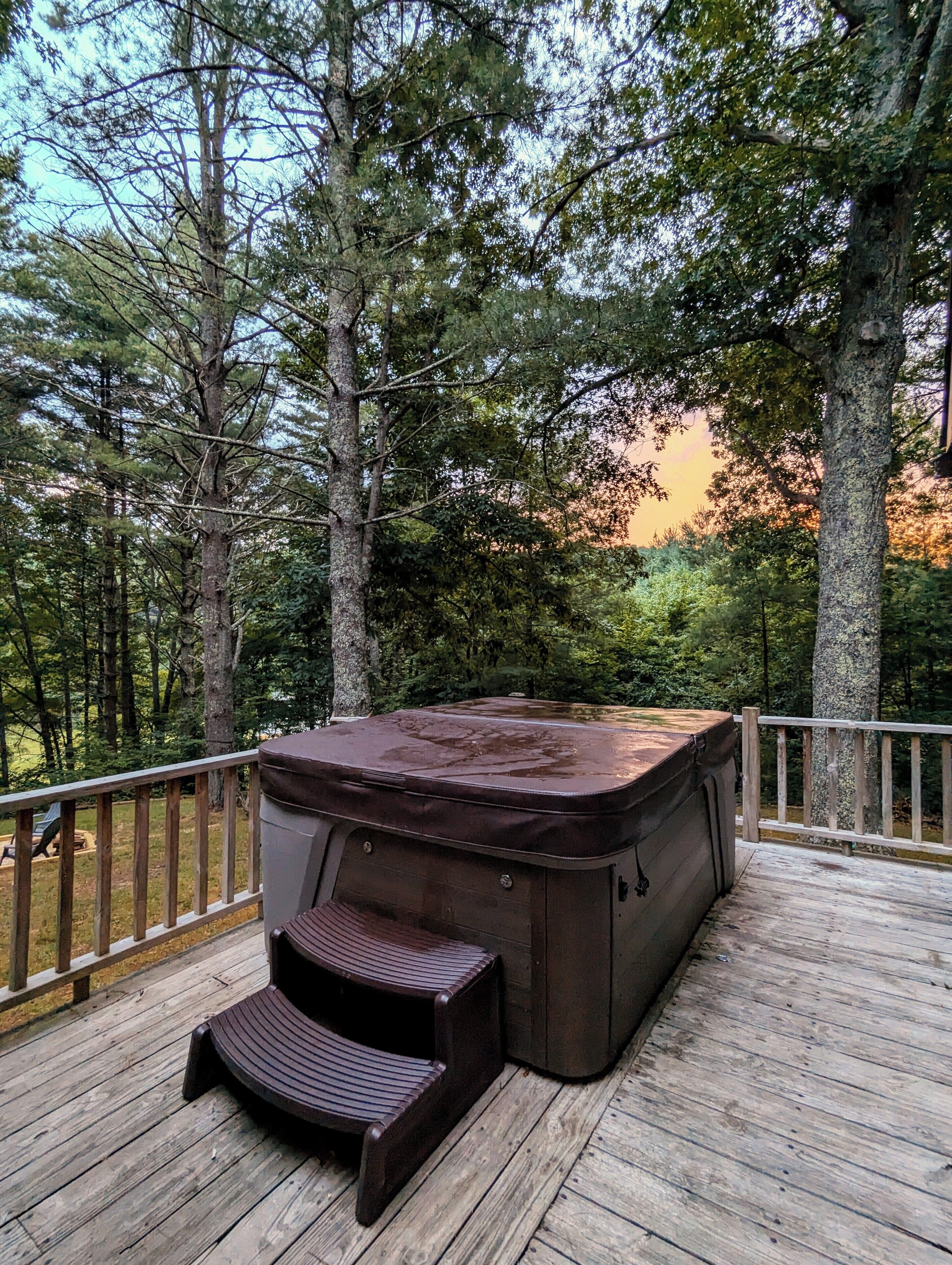 A hot tub on a wooden deck surrounded by trees.