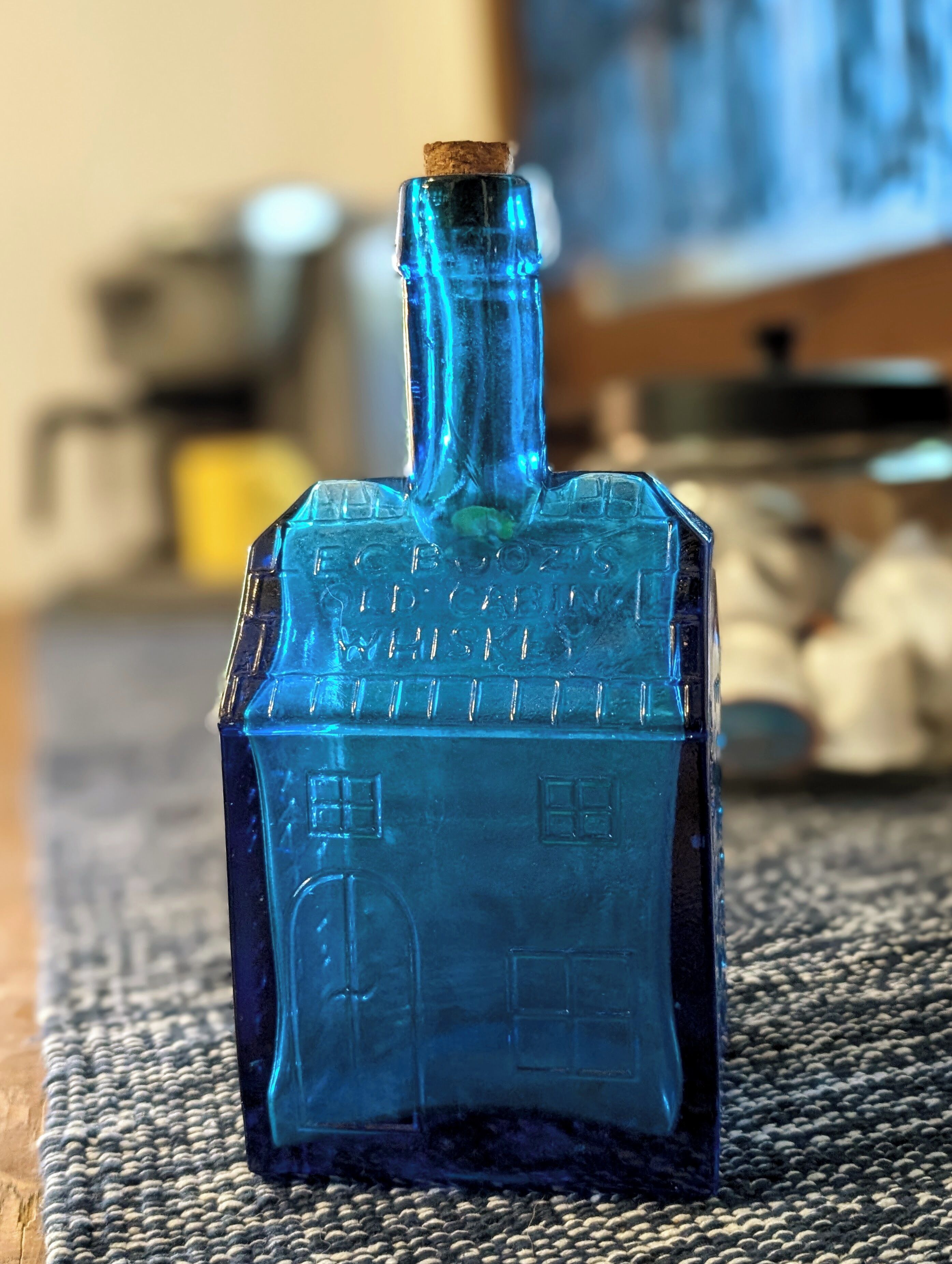 Una botella de vidrio azul con tapón de corcho sobre una superficie rugosa.