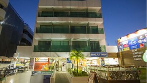 A multi-story hotel with a modern design, featuring a central atrium with a staircase and a small palm tree. - Israel Tambaú - APTO Luxuoso Beira Mar  (João Pessoa)