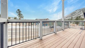 A wooden deck with metal railings, a clear sky, and a view of a mountainous landscape.