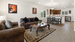 A modern living room with a brown leather sofa, a wooden coffee table, and a zebra-patterned rug.