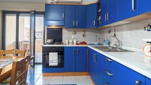 A modern kitchen with blue cabinets, a stove, and a sink. - Terrazza sul Mare - Appartamento (Mascali)