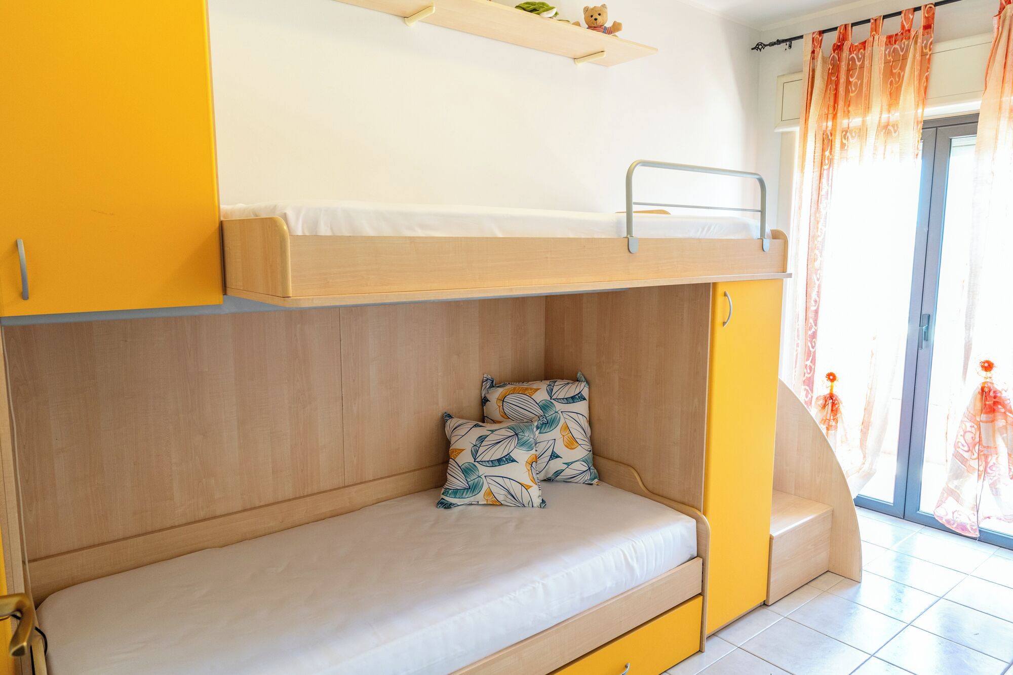 A bunk bed with a lower level bed and a shelf above.