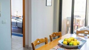 A dining area with a table set for two, a bowl of lemons, and a view through a window. - Terrazza sul Mare - Appartamento (Mascali)