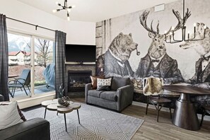Ein modernes Wohnzimmer mit Kamin, einer großen Wandmalerei von Hirschen und einem Essbereich.