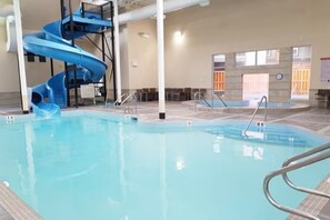 Ein Hallenbad mit einer blauen Spiralrutsche und Sprungbrett.