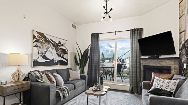 A modern living room with a sofa, a coffee table, a flat-screen TV, and a fireplace. - ★Mountain Haven★Pool&HotTub☆King Bed☆AC☆BBQ/Patio! (Canmore)