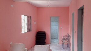 A room with pink walls, a window with blinds, a stack of black mats, a metal chair, and a door leading to another room. - Casa com Piscina em Mairiporã , (Mairiporã)