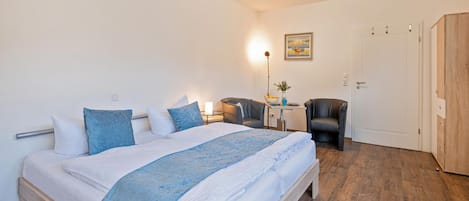 Un dormitorio con cama, mesitas de noche, escritorio, silla y armario.