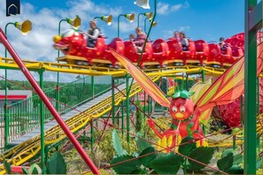 Eine Achterbahn mit roten Wagen und einer großen Drachenfigur im Vordergrund.