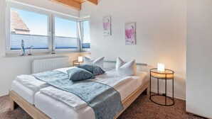 A bedroom with a bed, bedside tables, a window with blinds, and artwork on the wall. - Ferienwohnung 02 - Kimpi (Koserow)