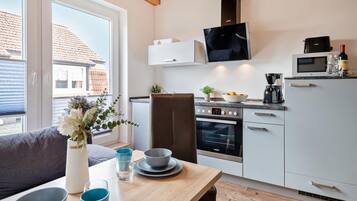 Een moderne keuken met een ingebouwde oven, magnetron en een eethoek met tafel en stoelen.