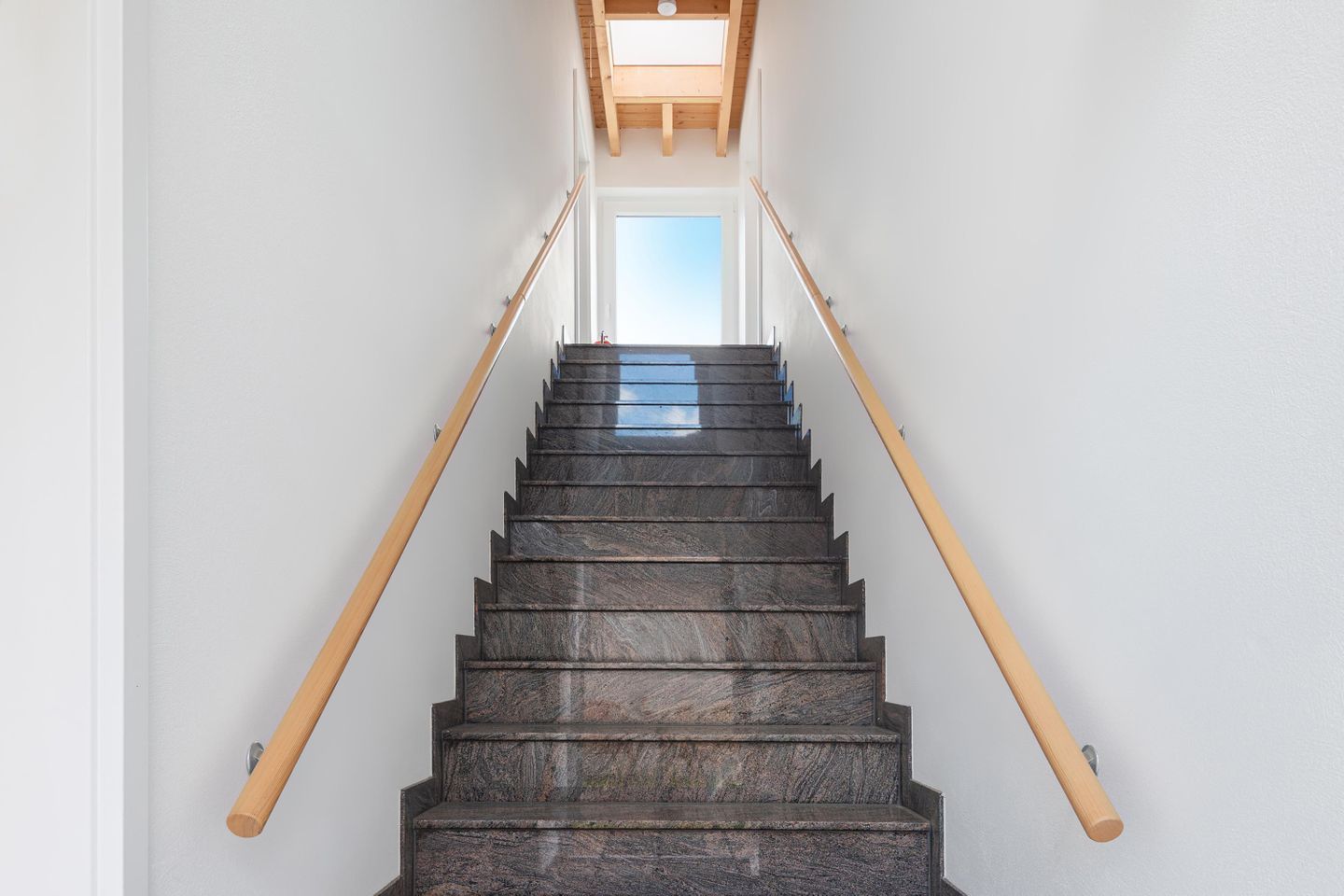 Eine Treppe mit hölzernen Geländern und einem Oberlicht am oberen Ende.