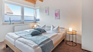 Een slaapkamer met een bed, nachtkastjes, een raam met zonwering en kunst aan de muur.