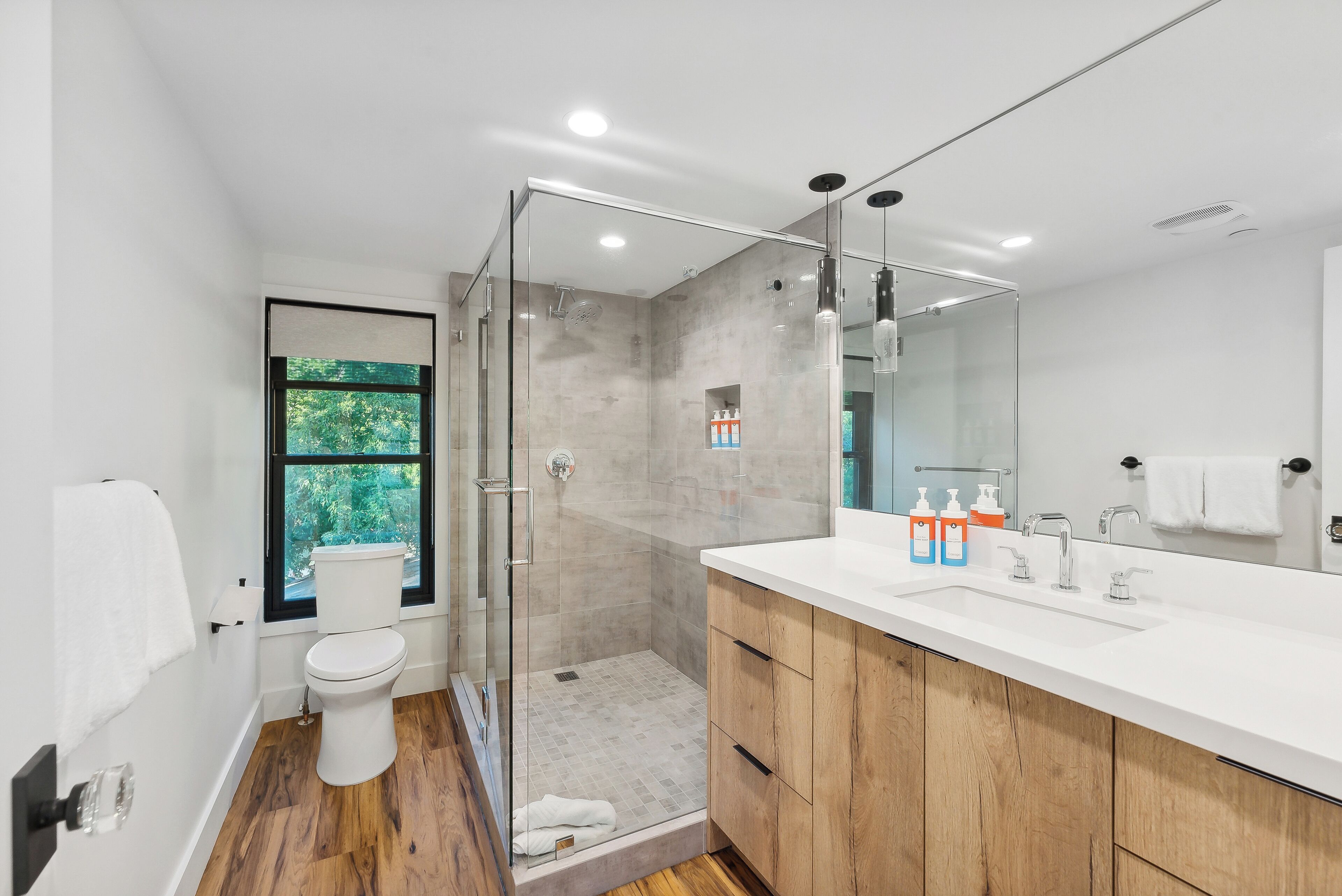 Une salle de bain moderne avec une douche à parois de verre, un lavabo blanc et des meubles en bois.