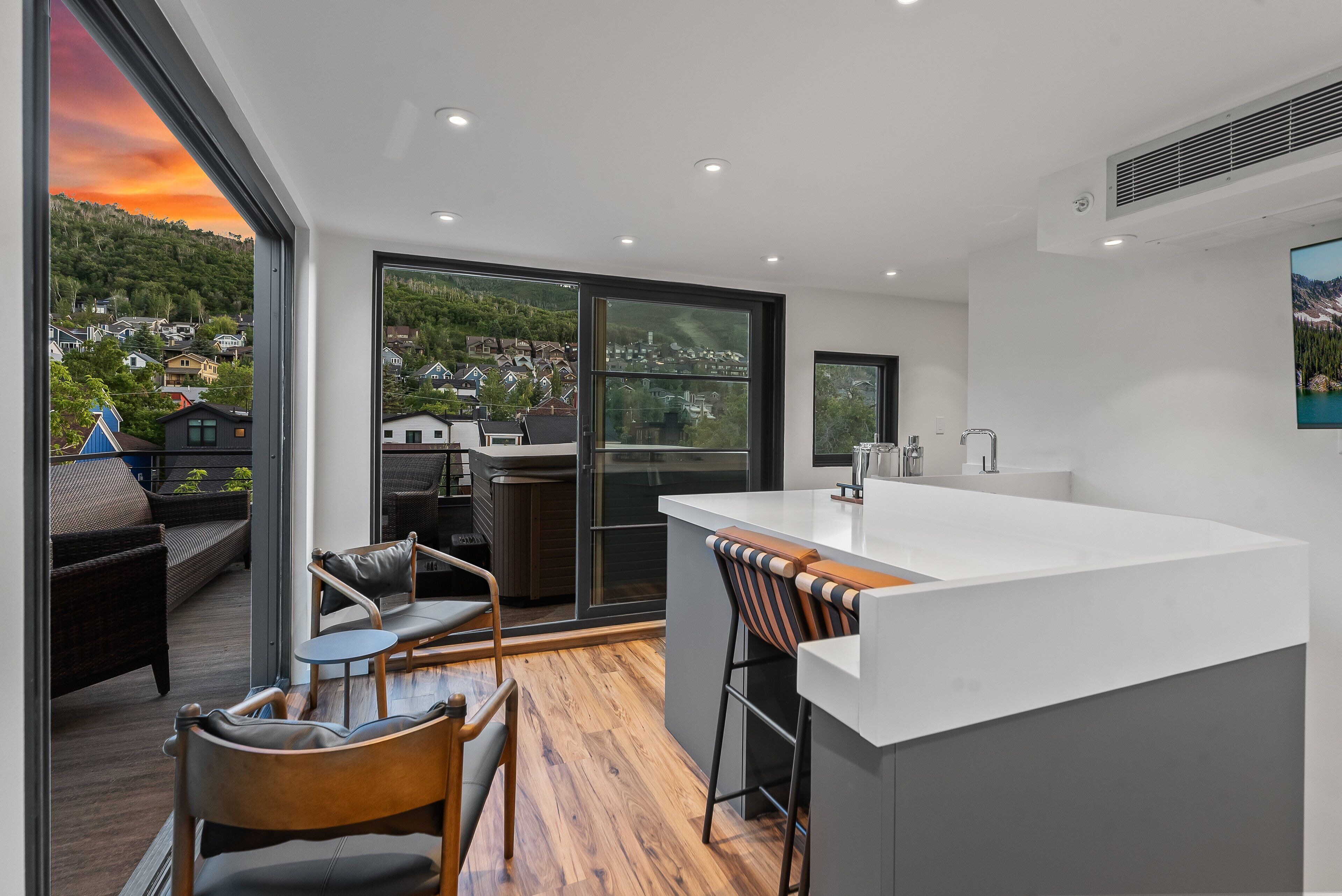 Een moderne keuken met een groot schiereiland, schuiframen naar een balkon en uitzicht op een heuvelstad.