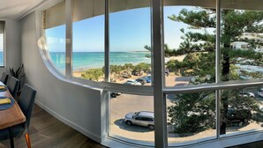 Un espace repas offrant une vue sur la plage et l’océan grâce à de grandes fenêtres.