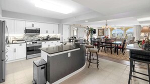 Une cuisine moderne avec des meubles blancs, des appareils en acier inoxydable et un îlot central.