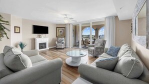 Un salon moderne avec une cheminée, deux canapés, une table basse et un téléviseur.