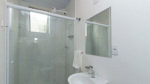 Une salle de bain avec une douche à parois de verre, un lavabo blanc et un miroir.