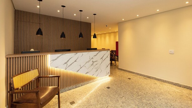 Un espace d'accueil doté d'un comptoir en marbre, d'un mur avec des lambris en bois et d'un coin salon comprenant un banc et une chaise.