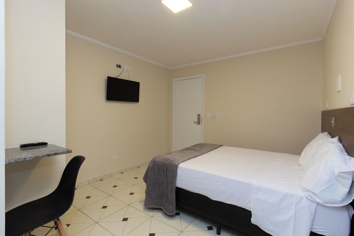 Ein kleines, sauberes Zimmer mit einem Bett, einem Schreibtisch und einem Stuhl.