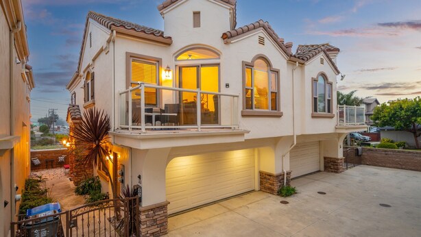 Une maison à deux étages avec un balcon, un garage et un petit patio.