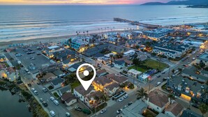 Une vue aérienne d’une ville côtière, avec une jetée imposante qui s’avance dans l’océan, entourée d’immeubles résidentiels et d’un parking.
