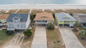 Zona residencial frente al mar, con casas, vista despejada del océano y una playa de arena.