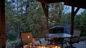 Un patio al aire libre con una mesa de vidrio, sillas y una chimenea integrada.